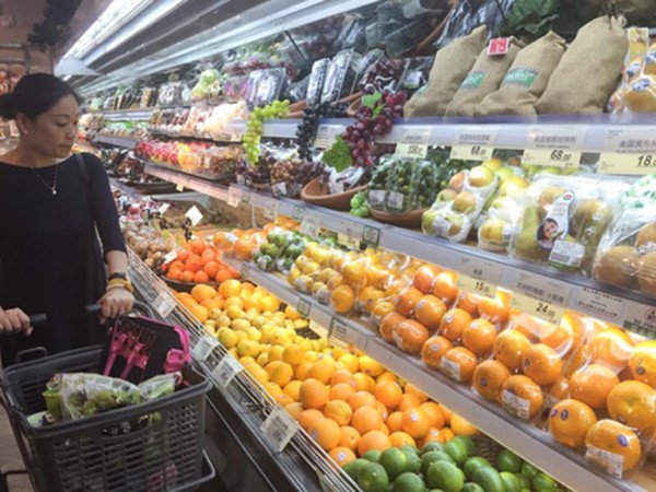 Một khách hàng đang xem hoa quả nhập khẩu tại siêu thị ở Thượng Hải. Ảnh:Nikkei