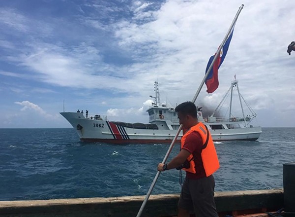 Một nhà hoạt động Philippines cầm quốc kỳ khi tàu hải cảnh Trung Quốc áp sát ở bãi cạn Scarborough, cách đảo chính Luzon của Philippines 230 km, tháng 6/2016. Ảnh:AFP.