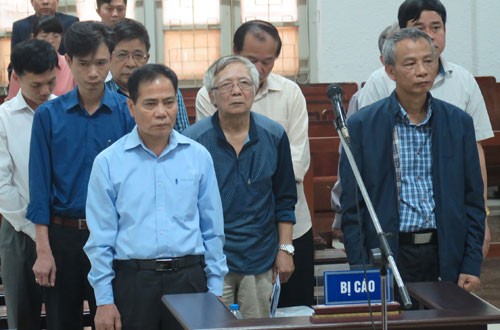 Bị cáo Trung (áo xanh, hàng đầu bên trái) và tám đồng phạm tại tòa.