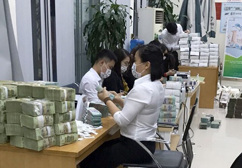 Cán bộ ngân hàng đếm tiền thu giữ được của Phan Sào Nam tại Quảng Ninh. Ảnh: CAND