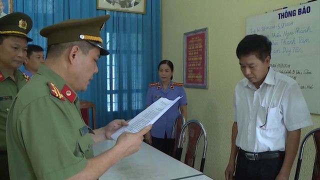 Ông Trần Xuân Yến (áo trắng), Phó Giám đốc Sở Giáo dục và Đào tạo tỉnh Sơn La, nghe tống đạt quyết định khởi tố bị can. (Ảnh do Bộ Công an cung cấp).