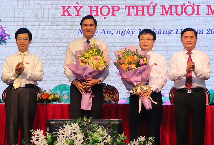 Ông Hoàng Nghĩa Hiếu (thứ hai từ trái sang) và ông Bùi Đình Long (thứ ba từ trái sang) nhận hoa chúc mừng.