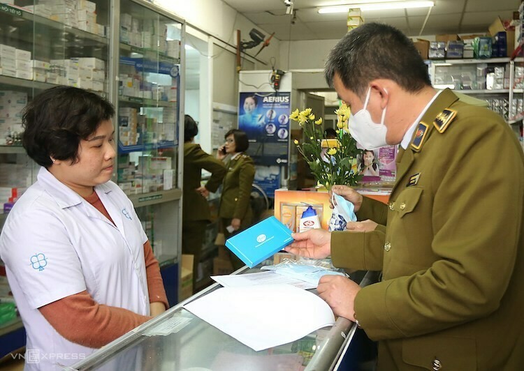 Cán bộ quản lý thị trường kiểm tra giá bán khẩu trang y tế tại một nhà thuốc ở Hà Nội.
