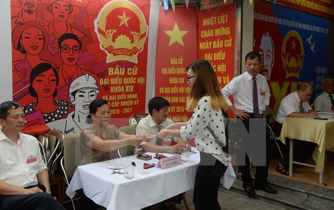 Cử tri Việt Nam nhận phiếu bầu tại một điểm bầu cử ở thủ đô Hà Nội ngày 22/5. (Ảnh: AFP/TTXVN)