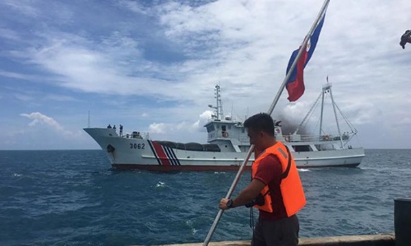 Một nhà hoạt động Philippines giơ cao lá cờ của nước này khi một tàu bảo vệ bờ biển Trung Quốc đi qua. Ảnh:AFP