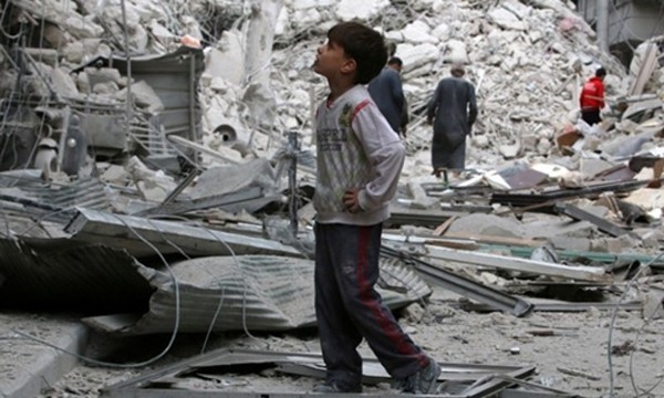 Một cậu bé đứng xem các căn nhà bị hư hại nặng nề sau đợt không kích nhằm vào phe nổi dậy tại Aleppo. Ảnh: Reuters.