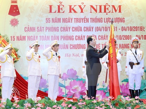 Chủ tịch nước Trần Đại Quang gắn Huân chương Bảo vệ Tổ quốc hạng Nhất lên lá cờ truyền thống của Cục Cảnh sát phòng cháy chữa cháy. (Ảnh: Nhan Sáng/TTXVN)