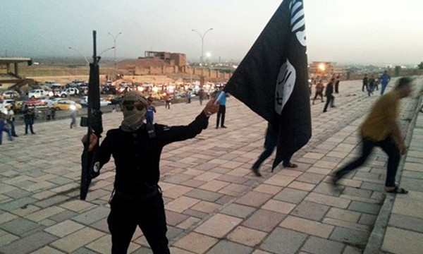 Một tay súng cầm cờ IS trên đường phố Mosul sau khi nhóm chiếm giữ thành phố hồi tháng 6/2014. Ảnh: Reuters