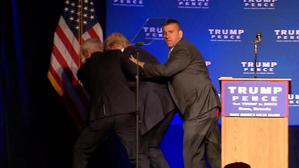 Ông Trump được các nhân viên an ninh đưa về phía sau sân khấu khi đang phát biểu. Ảnh: Reuters