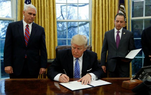 Ông Trump ký sắc lệnh hành pháp (executive order) dưới sự chứng kiến của Phó tổng thống - Mike Pence (trái) và Chánh Văn phòng Nhà Trắng -Reince Priebustại Phòng Bầu dụcngày 23/1 (theo giờ Washington). Ảnh:Reuters