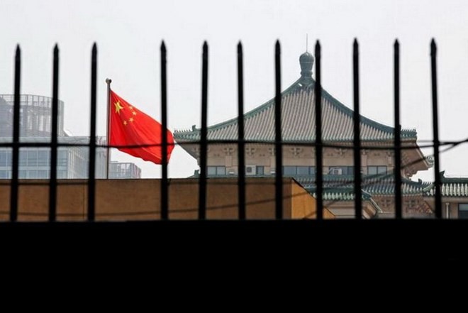 Quốc kỳ của Trung Quốc rực rỡ sau hàng rào của trụ sở của Ủy ban Cải cách và Phát triển quốc gia (NDRC) ở Bắc Kinh. (Nguồn: Reuters)