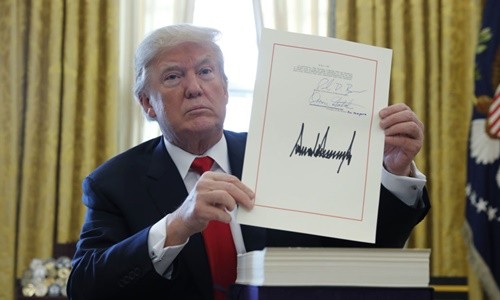 Tổng thống Mỹ Donald Trump cầm bản cải cách thuế với chữ ký của ông tại Phòng Bầu dục, Nhà Trắng, ngày 22/12. Ảnh:Reuters.