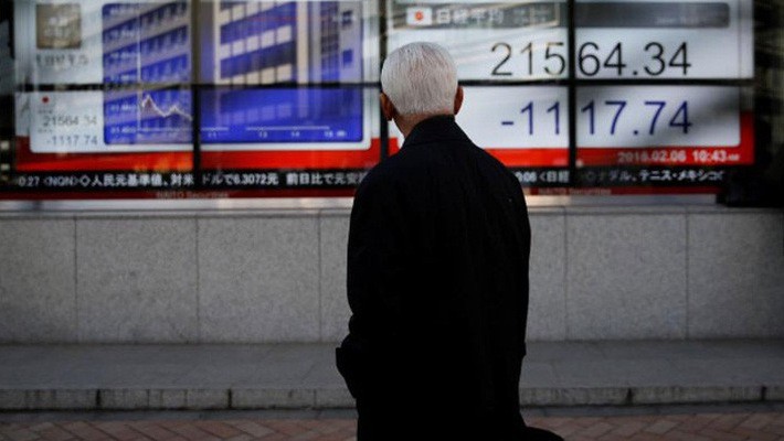 Một người đàn ông theo dõi một bảng giá chứng khoán trên đường phố ở Tokyo, Nhật Bản hôm 6/2 - Ảnh: Reuters.