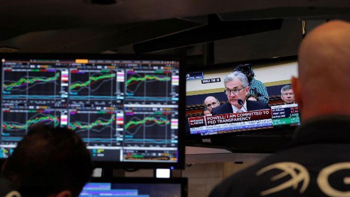 Hai nhà giao dịch cổ phiếu trên sàn NYSE ở New York đang theo dõi phiên điều trần của Chủ tịch FED Jerome Powell qua màn hình TV ngày 27/2 - Ảnh: Reuters.
