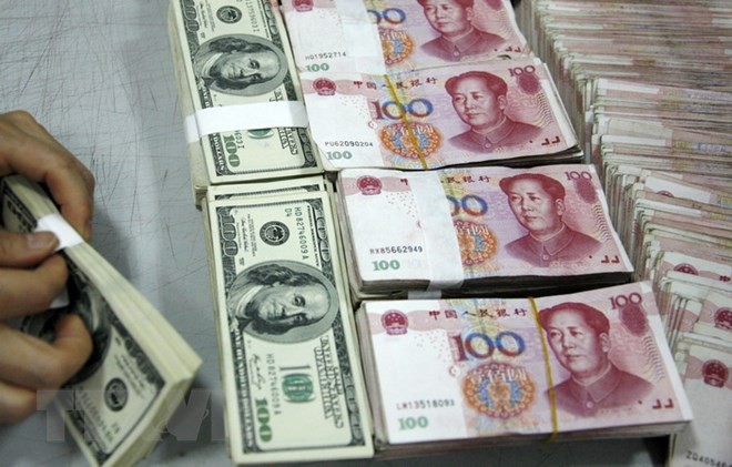Kiểm tiền nhân dân tệ (phải) và đồng USD (trái) tại ngân hàng ở tỉnh An Huy, Trung Quốc. (Nguồn: AFP/TTXVN)