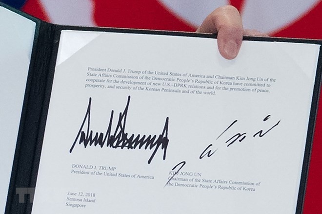 Văn kiện chung lưu lại chữ ký của Tổng thống Mỹ Donald Trump (trái) và của nhà lãnh đạo Triều Tiên Kim Jong-un (phải) tại Sentosa, Singapore ngày 12/6. (Nguồn: AFP/TTXVN)