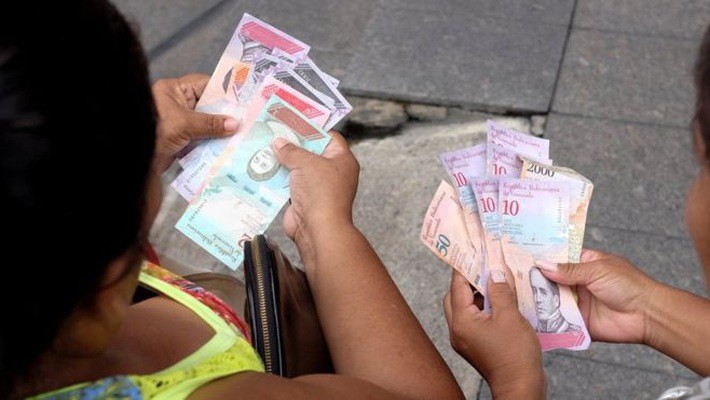Hai người phụ nữ trên đường phố Caracas ngày 21/8 đang xem những đồng Bolivar mệnh giá mới - Ảnh: Reuters.