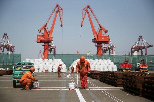 Công nhân đang sơn lại nền tại một cảng của Thanh Đảo, Sơn Đông, Trung Quốc. Ảnh:Reuters