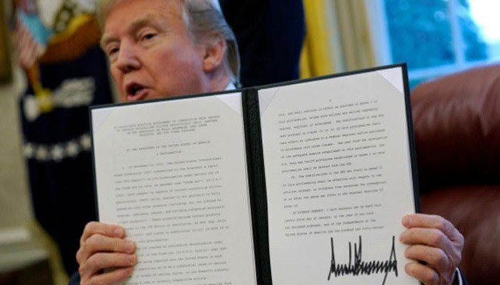 Tổng thống Mỹ Donald Trump và sắc lệnh mà ông ký về áp thuế quan lên máy giặt và tấm pin năng lượng mặt trời nhập khẩu vào Mỹ, tại Nhà Trắng, hôm 23/1/2018 - Ảnh: Reuters.