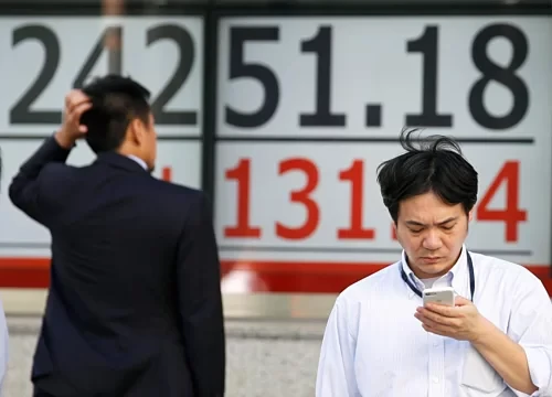 Một người đàn ông xem bảng điện tử bên ngoài một công ty môi giới chứng khoán ở Tokyo. Ảnh:Reuters