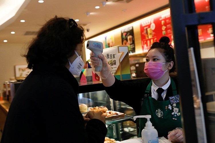 Nhân viên Starbucks kiểm tra thân nhiệt khách hàng tại Bắc Kinh.Ảnh: Reuters