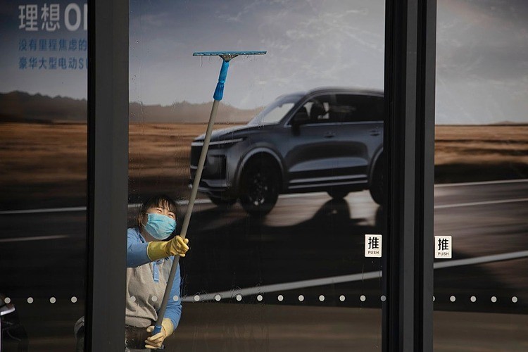 Công nhân lau cửa kính tại một showroom ôtô ế khách ở Bắc Kinh vào tháng 2/2020.Ảnh: AP