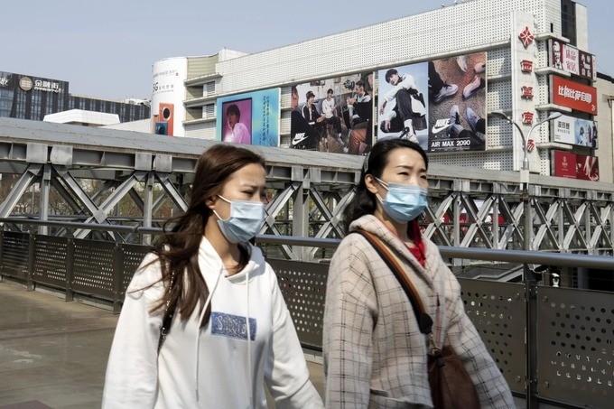Người dân đeo khẩu trang đi qua một trung tâm thương mại ở Trung Quốc. Ảnh: Bloomberg