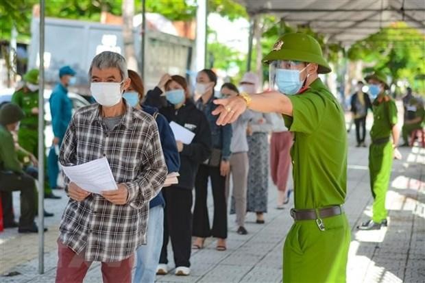 Hướng dẫn người tiêm thực hiện nghiêm việc phòng, chống dịch COVID-19 tại điểm tiêm Trung tâm Văn hóa quận Sơn Trà, Đà Nẵng. Ảnh: TTXVN
